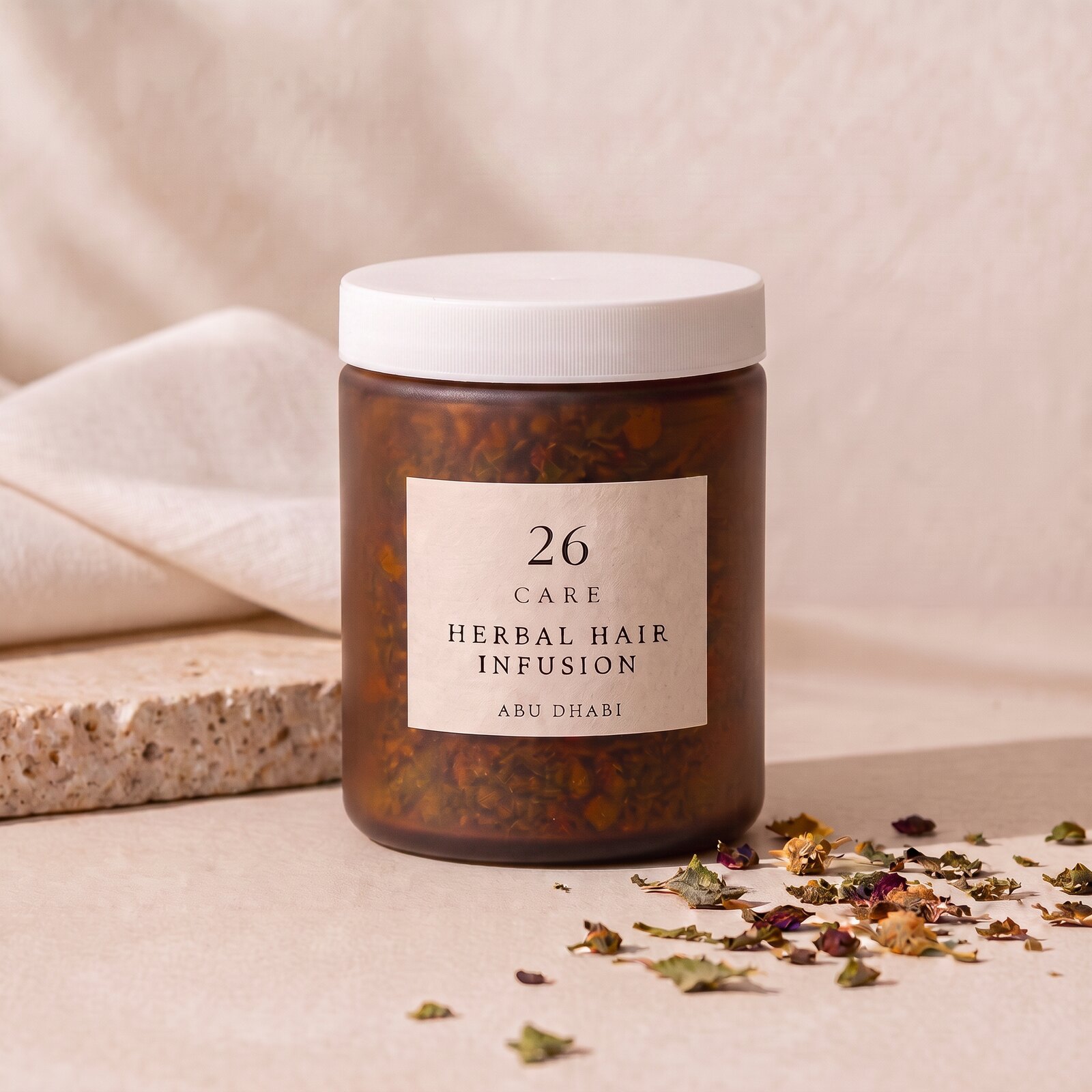 26 Care Herbal Hair Infusion in a frosted amber jar with cream label and loose dried botanicals beside it — Front — lid closed